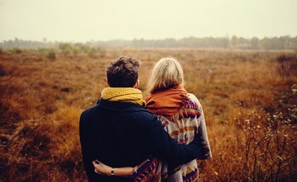 A couple hugging in a field.