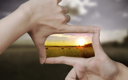 Two hands framing the sunset trying to savor life.