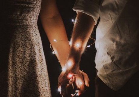 A couple holding hands with lights around their arms.