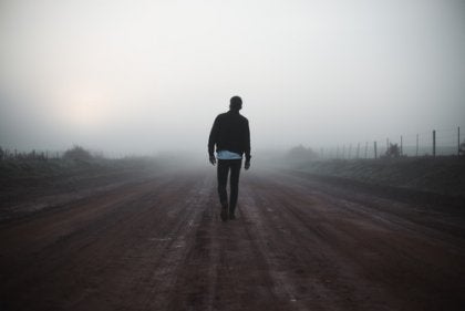 A man walking down a foggy road.