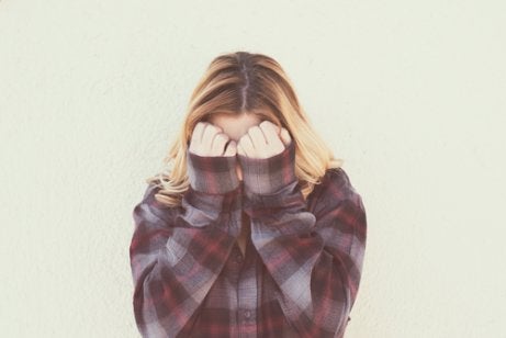 A woman covering her face with her hands.