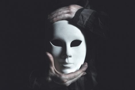 A person holding a white porcelain mask.