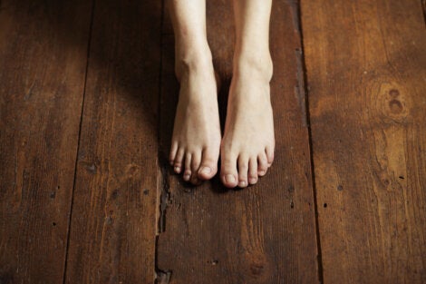 A person with their feet on a wooden floor.