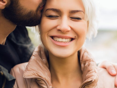 A man kissing a woman on the side of her head.