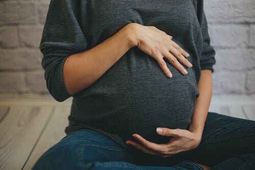 A pregnant woman grabbing her belly.