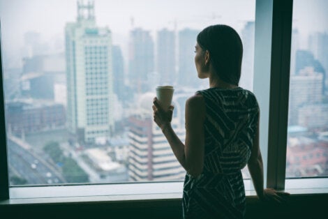 A woman drinking her coffee alone in her office.