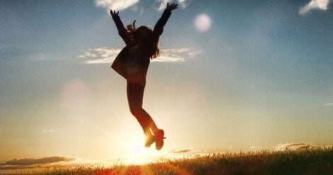 A woman jumping in front of the sun.