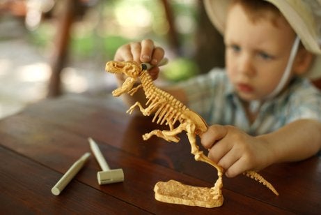 A boy playing with a model dinosaur. 