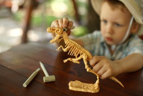 A boy playing with a model dinosaur.