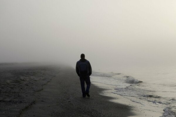 A man walking on the beach by himself.
