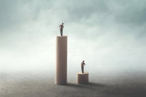 Two people standing on posts of different heights.