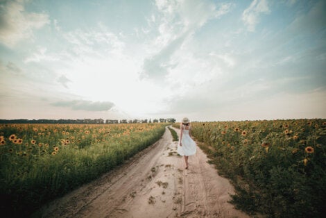 A woman walking down a dirt road.