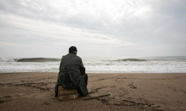 A person seated by the sea.
