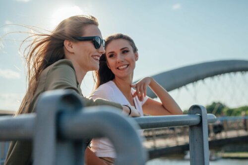 Two women talking on a bridge.