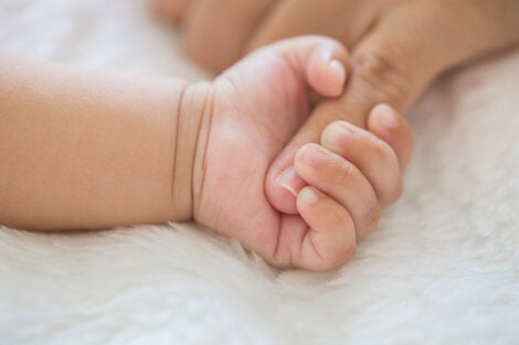 A baby gripping a finger.