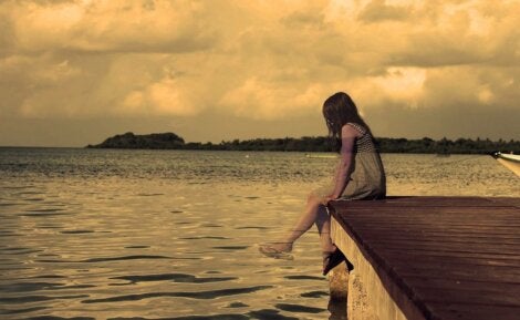 Bir iskelede tek başına oturan bir kız.