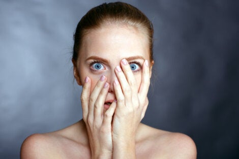 A woman with blue eyes covering her face.
