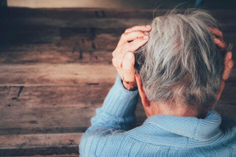 An elderly woman with her hands on her head.