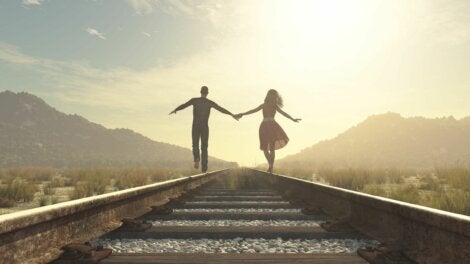 A happy couple walking along train tracks.