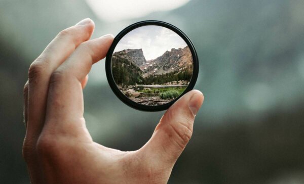 A hand holding a magnifying glass.