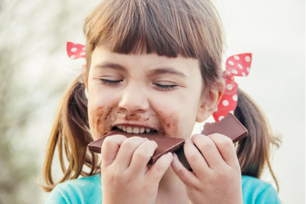 A happy girl eating chocolate, demonstrating you eat with your brain.