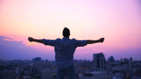 A man looking over a city at sunset.