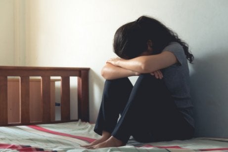 A woman crying on her bed.