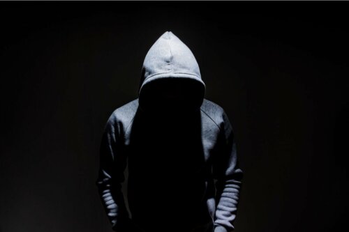 A man wearing a hoodie looking down.