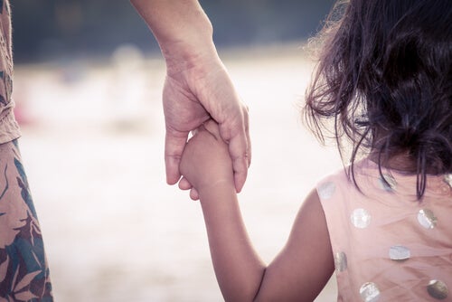A child holding an adult's hand.