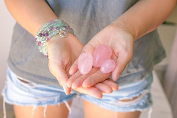 A woman holding three egg-shaped stones.