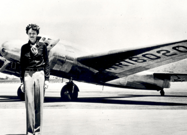 A picture of Amelia Earhart in front of plane.