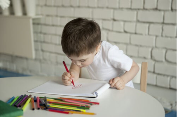 A boy drawing, showing the importance of children's drawings in their world.