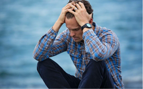 deniz kenarında elleri başında oturan adam