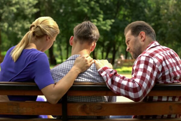 Three people sitting on a bench.