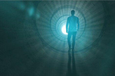 A man walking towards the light at the end of the tunnel.