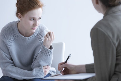 A sad person wielding a tissue, discussing with their therapist.