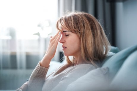 A woman pressing her fingers to her forehead.