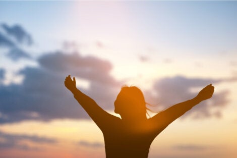 A woman with open arms thinking about if consciousness is a product of the brain.