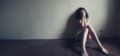 A woman with schizophrenia sitting on the floor.