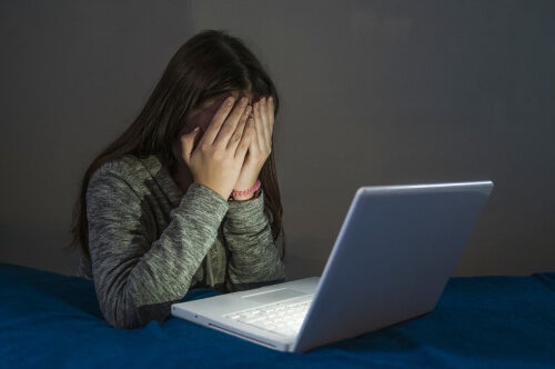 A woman covering her eyes at a computer.