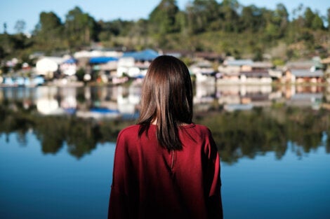 A woman looking across a lake towards a small village.