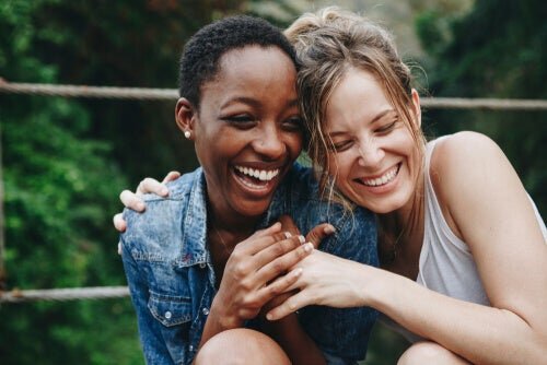 A lesbian interracial couple laughing and leaning on one another.