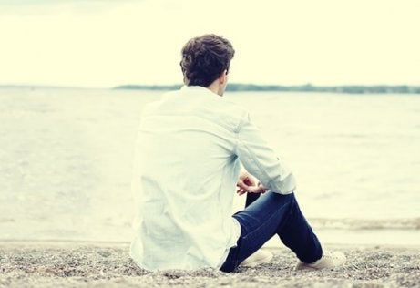 A guy sitting in front of the water.