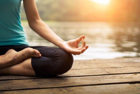 A woman meditating on a dock.
