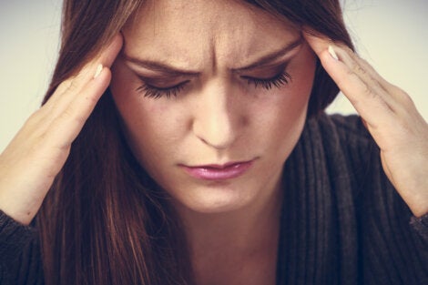 A frowning woman with a headache suffering sleep disruptions.