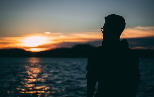 A man thinking about the importance of being compassionate with oneself while looking at the ocean.