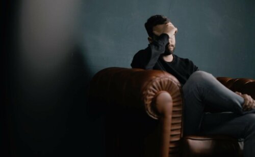 A man sitting on a couch feeling worried.