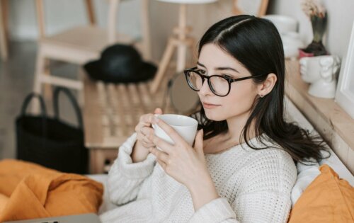 A woman wearing glasses drinking coffee.