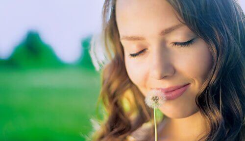 A woman sniffing a dandelion.