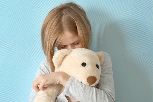 oyuncak ayısına sarılmış duran korkmuş kız çocuğu